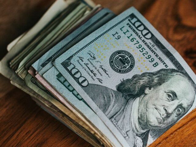 close-up of a folded stack of 100 dollar bills sitting on a wooden tabletop, innovative portfolios perspectives