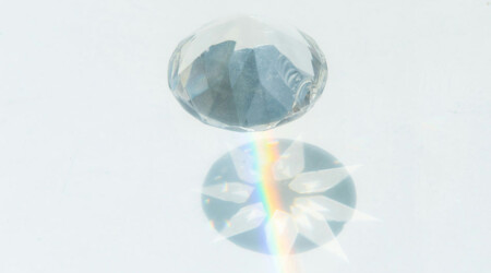 close up of clear crystal against white background, shadow and rainbow light appear on background, innovative portfolios perspectives