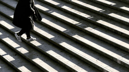 figure dressed in black climbing up marble stairs with light and shadows on the stairs, innovative portfolios perspectives