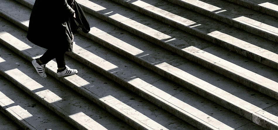 figure dressed in black climbing up marble stairs with light and shadows on the stairs, innovative portfolios perspectives